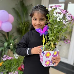 The best part of art is seeing the final creation. This young artist is proudly showing off her hand-painted flower pot, now a beautiful home for a real plant.