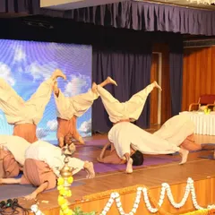 Students performing advanced variations of Sirsasana (headstand) on stage. Our anniversary celebrations are a testament to the progress and strength developed through consistent practice.