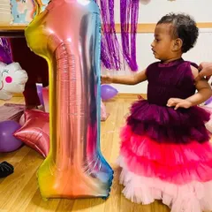 The younger sister celebrating her first birthday in her ombre tiered gown, designed to match her older sister's dress. The layered tulle is soft and perfect for a baby's first birthday party.
