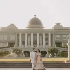 A wide shot of Mehul and Divya against the stunning architecture of Raffles Udaipur. This image showcases the scale and beauty of a luxury destination wedding in the heart of Rajasthan.