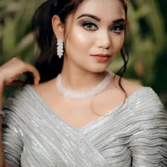 A classic and elegant close-up portrait of the bride. The soft, natural lighting beautifully highlights her makeup and the intricate details of her silver outfit and jewelry.