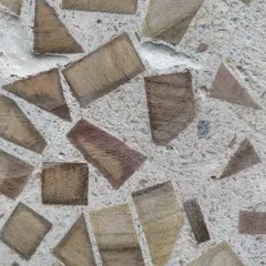 A close-up of the finished wood-waste concrete. The random pattern of wood chips creates a warm and tactile surface, turning a waste product into a beautiful architectural material.