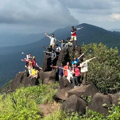 A fun and energetic group photo on the rocky summit of Kurinjal Peak.
