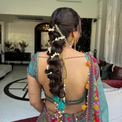 A playful yet traditional bubble braid for a Mehendi ceremony, woven with fresh mogra flowers and finished with vibrant tassels. This look is perfect for the bride who wants a fun, bohemian hairstyle that is still deeply rooted in Indian tradition.