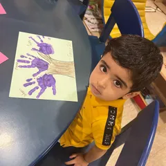 This little boy is proudly showing the family tree he made with his handprints. It's a beautiful and personal art project that helps children understand the concept of family in a creative way.