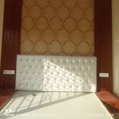 The same tufted headboard and wallpaper combination, showing the neat integration of the side tables and electrical points within the fluted panel frame.