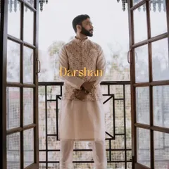 A full-length portrait of the groom, Darshan, framed by a beautiful doorway. His elegant ethnic wear and confident pose make for a striking image.