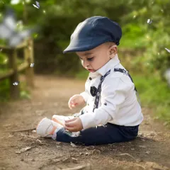 Dressed in a dapper outfit, this little boy is exploring a path in the park. The natural surroundings create a beautiful, soft background.