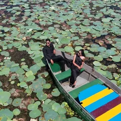 An epic drone shot from a serene pre-wedding shoot on a lake filled with lily pads. This aerial perspective shows the grand scale of the location and the quiet intimacy of the couple, creating a stunning visual contrast.