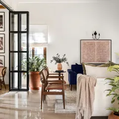 This living room is designed to be a tranquil oasis. The soothing color palette, plush cushions, and abundance of green plants create a sanctuary for unwinding and relaxation. The pop of blue from the sofa adds a touch of sophisticated color.