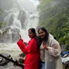 Two friends in their raincoats posing by a beautiful waterfall on the Bandaje trail. The monsoon season makes these falls even more spectacular.
