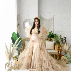 A beautiful solo portrait of the mom-to-be in our bright boho studio. She is wearing a beige ruffled gown that perfectly complements the earthy tones of the rattan furniture and decor.