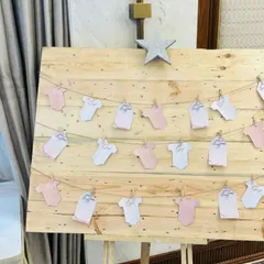 A creative way for guests to leave their wishes for the baby. We set up a rustic wooden board where notes written on baby onesie-shaped cards can be clipped, creating a charming and interactive display.