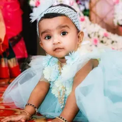An adorable photo of a baby girl at her naming ceremony, looking directly at the camera with her big, curious eyes.