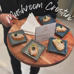 My staff presenting Mushroom Crostini on a wooden platter. Each crostini is topped with a creamy mushroom pâté, offering an earthy and savory bite for guests at the Dhruv Vaish event.