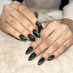 A deep green and black cat-eye design on almond-shaped extensions. This creates a stunning, galaxy-like depth and shimmer.