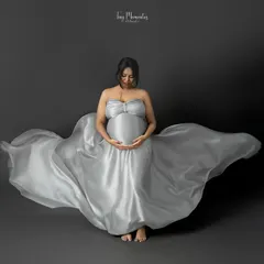 Seated in a pool of shimmering silver fabric, this portrait is all about serenity and the beauty of the maternal form. The flowing gown creates a sense of magic.