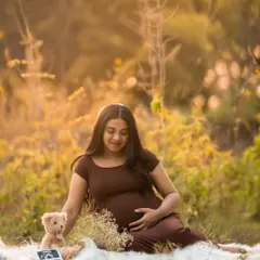 A sweet and sentimental shot featuring the baby's first ultrasound picture. This outdoor setup includes a teddy bear and soft blanket for a personal touch.