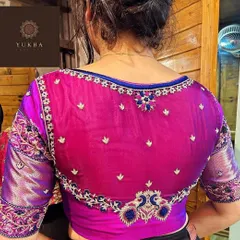 A modern and elegant design featuring a sheer net back on a magenta blouse. The delicate floral embroidery along the border and scattered motifs create a subtle yet captivating look.
