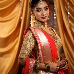 A complete bridal look featuring a classic hairstyle that complements the beautiful gold and red Kanjivaram saree. The hair is styled in a simple, elegant updo at the front with a traditional braid, allowing the statement jewelry and makeup to shine.