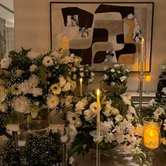 A beautiful tablescape featuring lush arrangements of white flowers and greenery, illuminated by the warm glow of numerous candles. This setup is perfect for an elegant dinner party or reception.