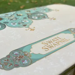 A close-up of the intricate sea-green and gold foil details on the exterior of the hamper box. This is the first thing your guests will see, and it makes a stunning impression.