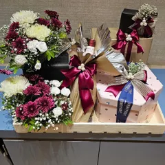 This large tray hamper was part of a corporate order for Shoppers Stop and Axis Bank. It includes a bottle of wine, gourmet food boxes, and a generous bouquet of fresh chrysanthemums, creating an impressive and abundant gift.
