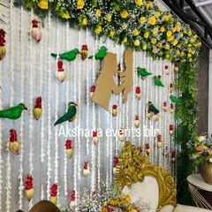 A detailed view of a baby shower backdrop. This image highlights the delicate work of the hanging jasmine garlands, the mother and child silhouette, and the cute parrot motifs.