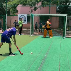 A junior player taking a penalty stroke against a fully-kitted goalkeeper. I focus on teaching the correct technique for both the shooter and the keeper in these high-stakes situations.