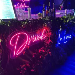 A bar that sets the mood. We used lush greenery and fun neon signs like 'Drunk In Love' to create a lively and photogenic beverage station.