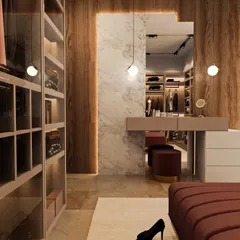 This walk-in closet combines rich wood paneling with soft pink cabinetry and a marble accent wall. The design includes a floating vanity and open, glass-fronted shelves for a high-end feel.