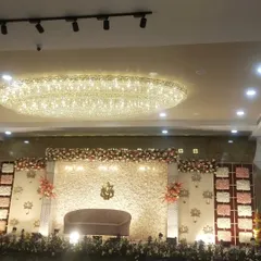 This image captures the entire reception hall, showing how the grand stage and the overhead chandelier work together to create a luxurious ambiance.