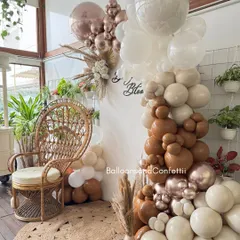 A closer look at the boho-chic 'Baby in Bloom' decor. The organic balloon garland in earthy tones is the perfect complement to the natural textures of the wicker chair and jute rug.