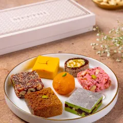 A close-up of various Indian sweets like ladoo, barfi, and peda from Meethi India. This shot highlights the variety and craftsmanship of the confections.