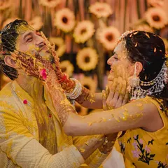 The playful side of a Haldi ceremony, where the couple lovingly smothers each other with turmeric paste against a backdrop of sunflowers. These are the fun, uninhibited moments that make a wedding memorable.