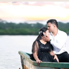 A tender moment captured during a pre-wedding shoot, with the groom kissing the bride's forehead as they sit in a small boat on a calm lake.