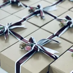 Elegantly wrapped gift boxes with rich burgundy and white ribbons, perfect as sophisticated favors for a wedding reception or engagement party.