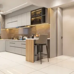 A minimalist breakfast bar extension from the main counter provides a cozy dining spot in this L-shaped kitchen. The combination of light wood and grey cabinetry creates a modern, Scandinavian-inspired look.