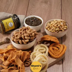 Welcome to my snack-arena. This board features a variety of my crunchy snacks like Kodbale, Ribbon Murukku, and peanuts, paired with my special homemade chutney. It's a perfect platter for sharing with loved ones.