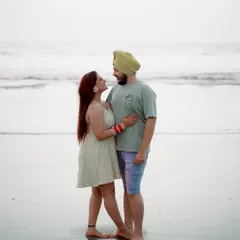 A classic beach portrait. The couple stands together, smiling, creating a beautiful memory of their time in Goa. The bride's red bangles add a lovely pop of color.