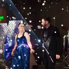A magical moment for the couple on their Sangeet stage, surrounded by futuristic decor and a gentle fall of artificial snow, creating a romantic and memorable scene.