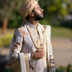 A close-up view of a groom's wedding attire. This sherwani features dense, intricate embroidery in white and gold thread, creating a rich texture. I paired it with a traditional pearl necklace to complete the royal look.