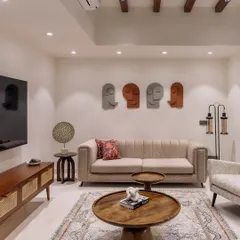 This family lounge in 'Project Lily' features a comfortable beige sofa, artistic face sculptures on the wall, and warm wooden furniture, creating a cozy and personal atmosphere.