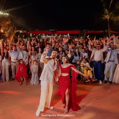 The entire wedding party poses for a massive group photo on the dance floor at a vibrant beachside reception in Goa.