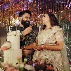 A sweet moment during the cake-cutting ceremony at the reception. The disco balls and glittering backdrop add to the celebratory feel.