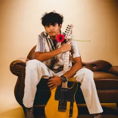 A portrait of a musician with his guitar, captured against a warm, seamless backdrop. Our studio is perfect for creating artist profiles and album art.