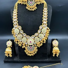 This high-quality bridal set features beautiful floral motifs with ruby-red center stones and uncut polki style work. The rental package includes a matching choker, a long necklace, elegant jhumkas, and a maang tikka, giving you a complete and coordinated royal look.