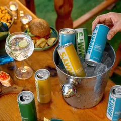 A lifestyle shot from the Jimmy's Cocktail campaign, capturing a relaxed outdoor party scene. The focus is on the products integrated into a social gathering, making them look like the perfect addition to any get-together.