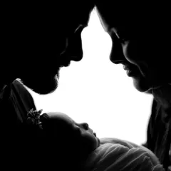 A powerful black and white silhouette of parents and their newborn. This artistic style creates a timeless image focused on the family's bond.