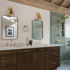 This bathroom in Saratoga is all about serene luxury. The double vanity with brass fixtures, the walk-in shower with textured green tiles, and the wood-beamed ceiling come together to create a calming, spa-like atmosphere.